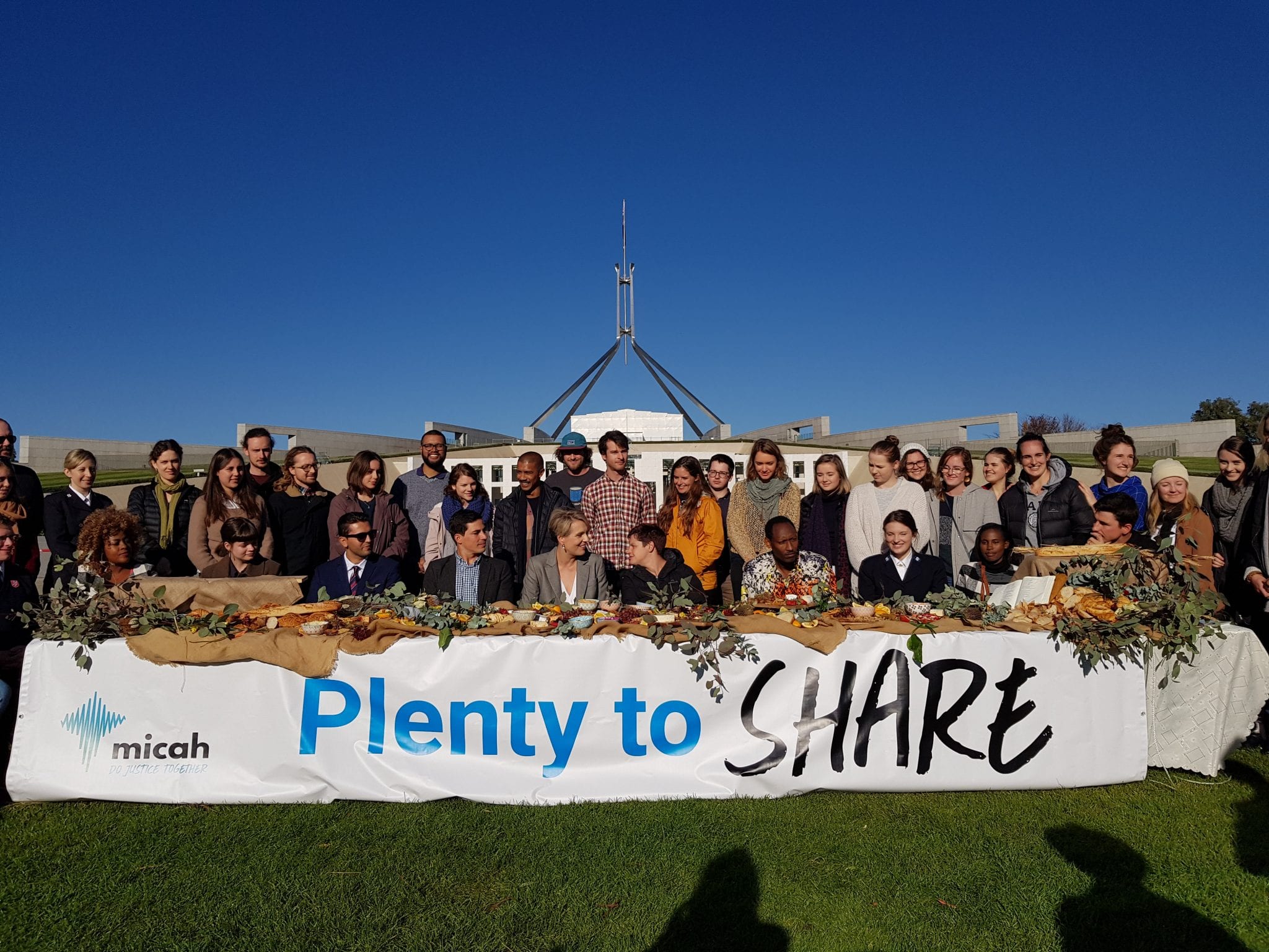 Stevie Wills and Tanya Plibersek sitting at the Micah Australia Table of Plenty with other Australians supporting the event
