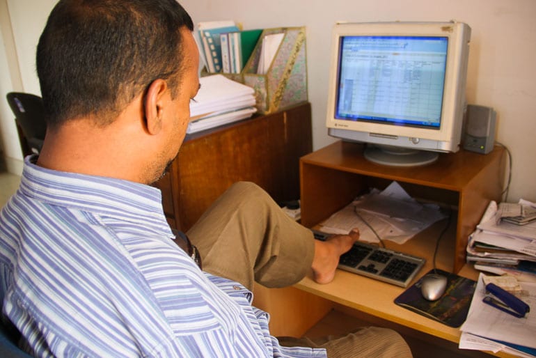 Man navigating a computer keyboard with his foot.