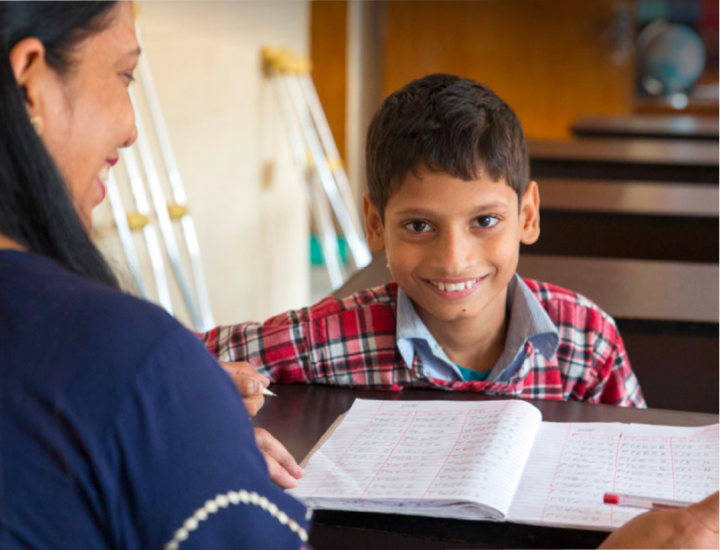 A young boy smiling, he has an open book in front of him