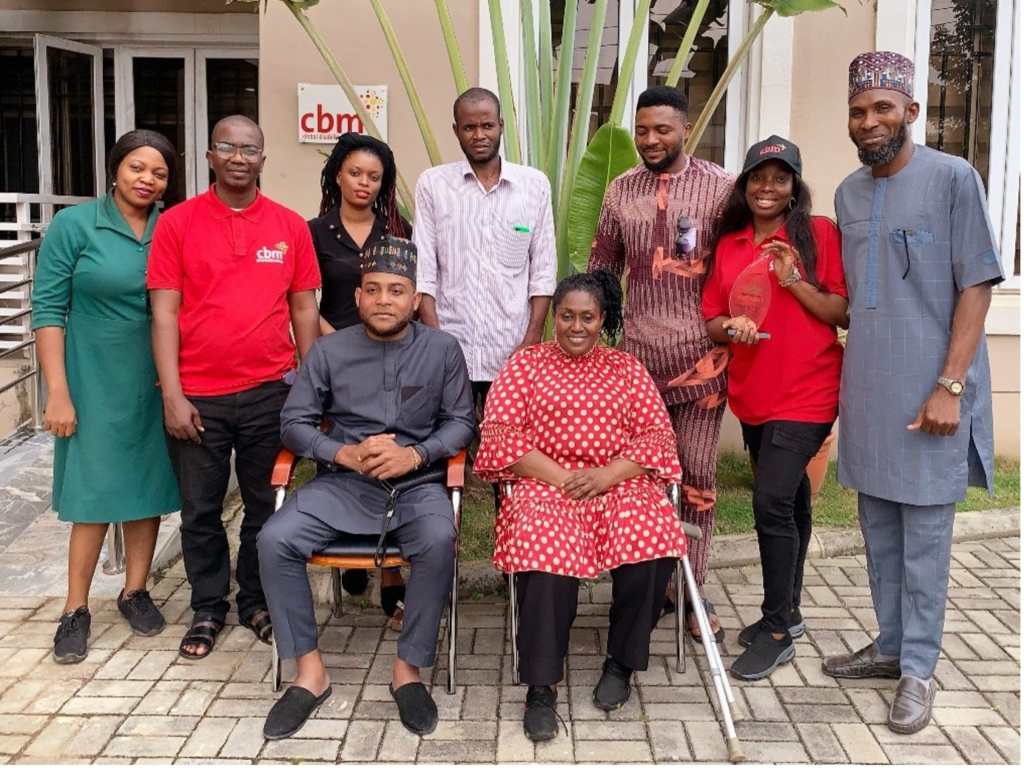 Nine members of the CBM Global Nigerian country team with their NNAD award for their work supporting the deaf community in Nigeria.