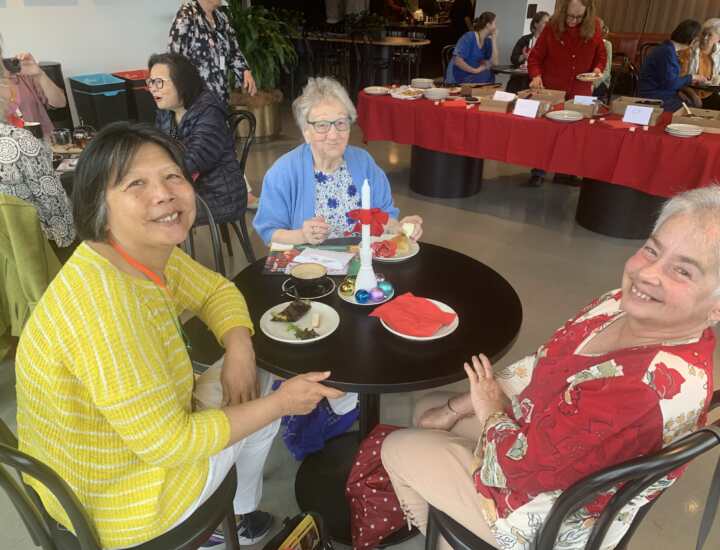 A volunteer team of three women enjoy tea together.
