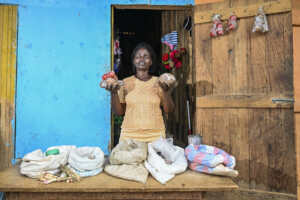 Jennifer a woman holding up sacks of maize  