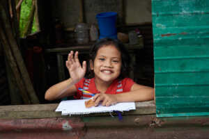 A girl smiling and waving at the camera