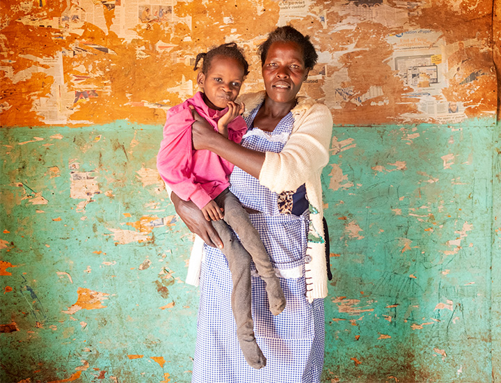 A woman in a blue dress holding her daughter in her arms.