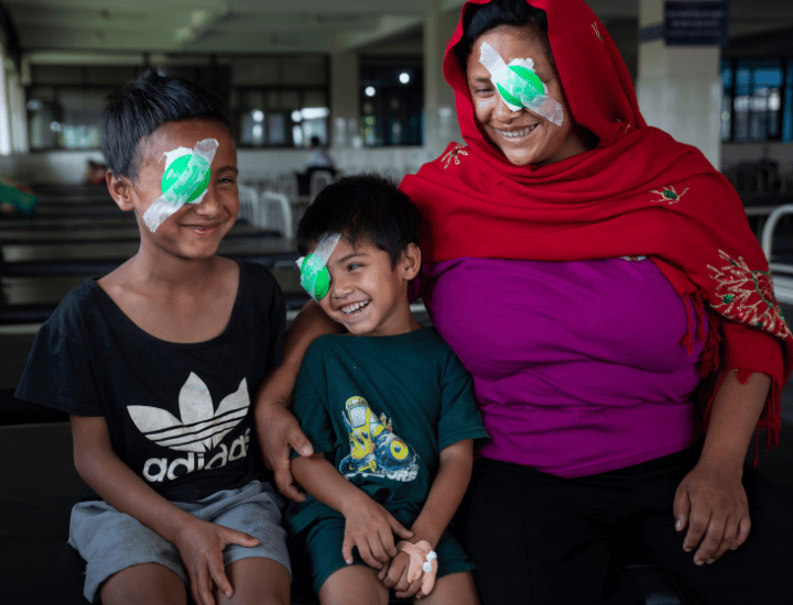 Goma and her two boys smiling with eye patches on