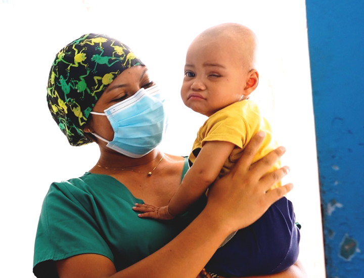 A nurse holding a child with no eye