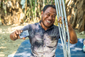 A picture of a man holding an ID card and a pair of crutches